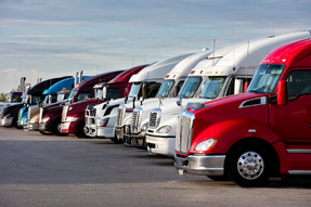 A parked row of semi trucks in a parking lot